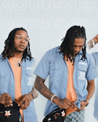 a man with dreadlocks and a hat is posing for a photo